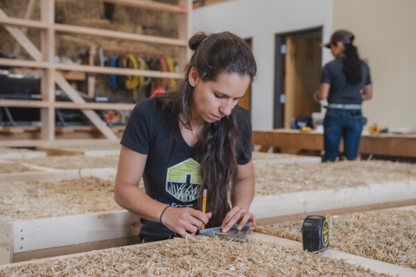 Employee Marina Rubio Herranz calculates measurements. The company’s straw bale insulation is made from organic grass grown on Aurora Farm and the timber framing is sourced from Fontaine Sawmill, a zero waste yard that harvests local, sustainably managed timber. Photo by Erica Houskeeper.